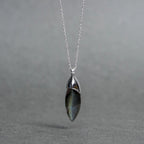 Celebrity-style sterling silver pendant with an elongated labradorite stone in a cap setting, hanging on a fine chain against grey.