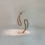 Gold snake-style ear crawler earring with black beaded detail